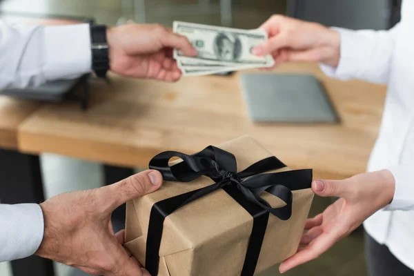 Visão parcial do empresário dando caixa de presente e dólares borrados para a mulher, conceito anti-corrupção — Fotografia de Stock
