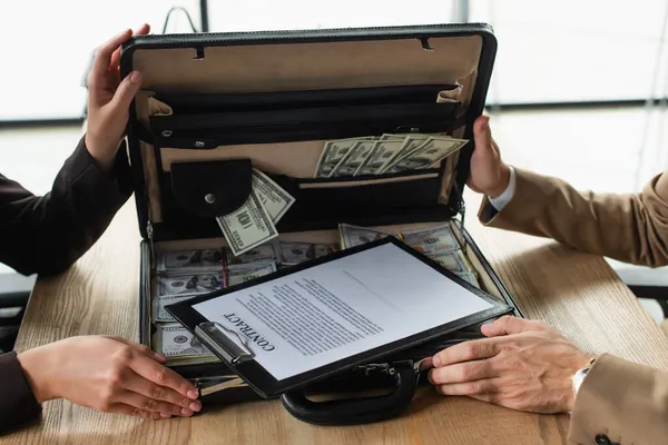 Partial view of business people near briefcase with dollars and contract, anti-corruption concept — Stock Photo