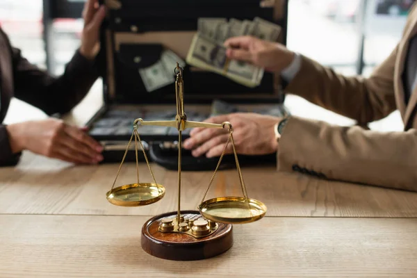 Selective focus of bronze justice scales near cropped business people near briefcase with dollars, anti-corruption concept — Stock Photo