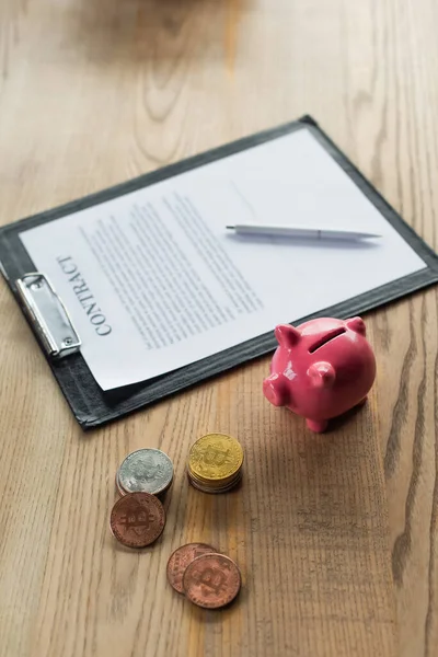 KYIV, UKRAINE - SEPTEMBER 22, 2021: high angle view of contract near piggy bank and bitcoins, anti-corruption concept — Stock Photo