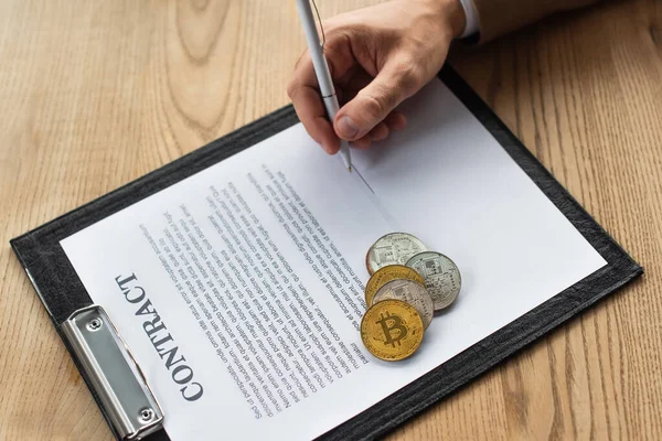 KYIV, UKRAINE - SEPTEMBER 22, 2021: top view of cropped businessman signing contract near bitcoins, anti-corruption concept — Stock Photo