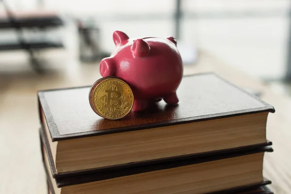 KYIV, UKRAINE - SEPTEMBER 22, 2021: piggy bank and bitcoins on codex books in office, anti-corruption concept — Stock Photo