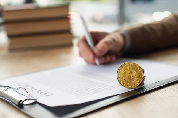 KYIV, UKRAINE - SEPTEMBER 22, 2021: cropped of blurred businessman signing contract near money and bitcoin, anti-corruption concept — Stock Photo