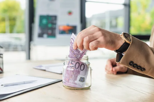 Cropped view of businessman putting euro banknotes into glass jar, anti-corruption concept — Stock Photo