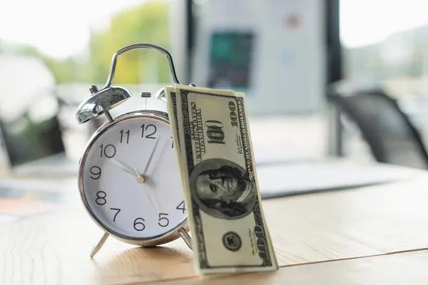 KYIV, UKRAINE - SEPTEMBER 22, 2021: dollar banknotes near retro alarm clock on office desk, anti-corruption concept — Stock Photo