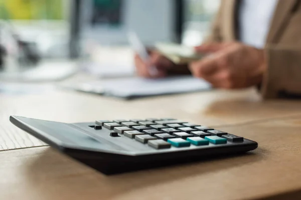 Selective focus of calculator near cropped accountant counting money on blurred background, anti-corruption concept — Stock Photo