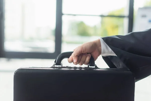 Cropped view of businessman holding briefcase in office, anti-corruption concept — Stock Photo