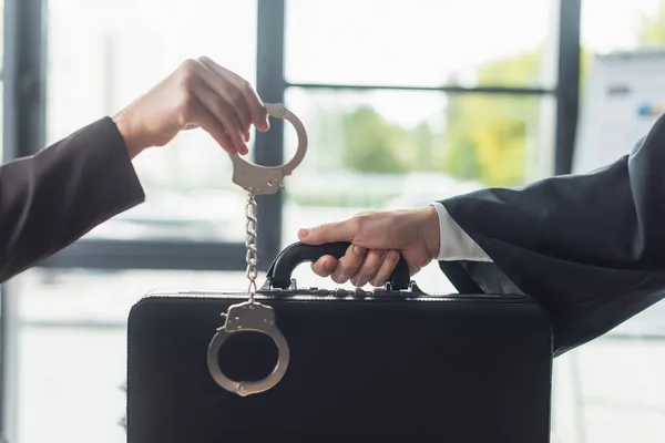 Cropped view of woman holding handcuffs near man with briefcase, anti-corruption concept — Stock Photo