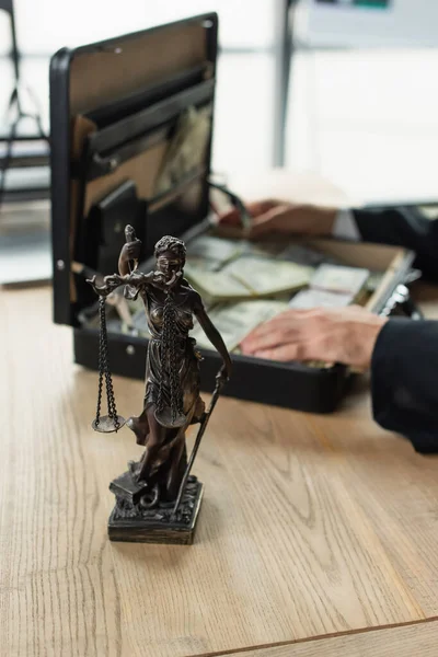 Selective focus of themis statue near cropped judge with money in briefcase on blurred background, anti-corruption concept — Stock Photo