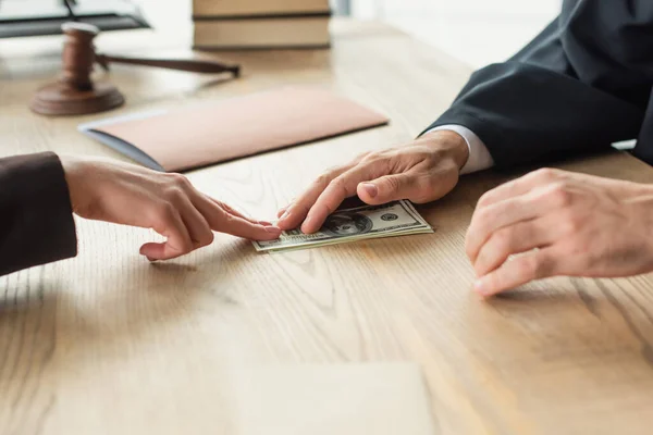 Partial view of woman giving bribe to judge near blurred gavel, anti-corruption concept — Stock Photo