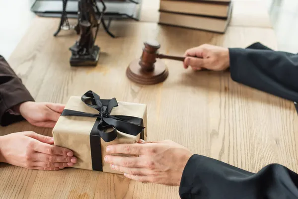 Partial view of lawyer holding gavel while taking gift box from client, anti-corruption concept — Stock Photo