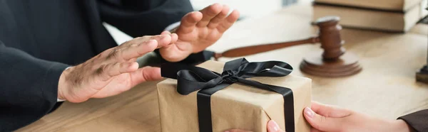 Partial view of judge showing refuse gesture near woman with gift box, anti-corruption concept, banner — Stock Photo