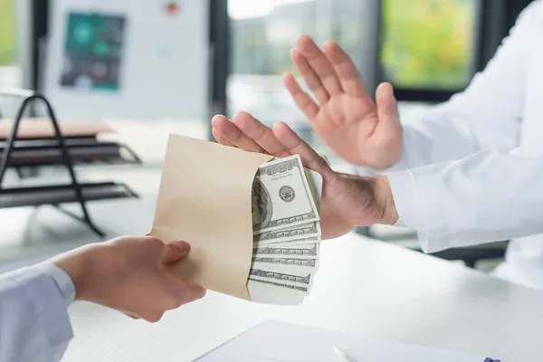 Cropped view of woman holding bribe near doctor showing stop gesture, anti-corruption concept — Stock Photo