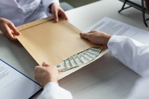 Visão cortada de médico tomando envelope com dinheiro do paciente, conceito anti-corrupção — Fotografia de Stock
