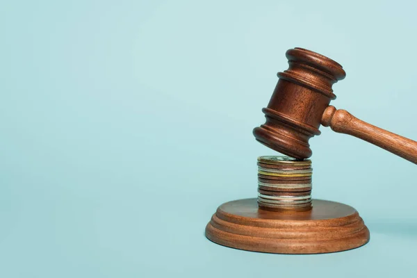 Wooden gavel on stacked golden and silver coins on blue, anti-corruption concept — Stock Photo