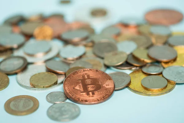 QUIIV, UCRÂNIA - SETEMBRO 22, 2021: foco seletivo de bitcoin perto de moedas de ouro e prata borradas espalhadas no azul, conceito anti-corrupção — Fotografia de Stock