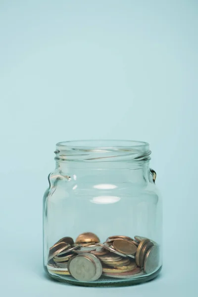 Pot en verre avec des pièces d'or et d'argent sur fond bleu, concept anti-corruption — Photo de stock