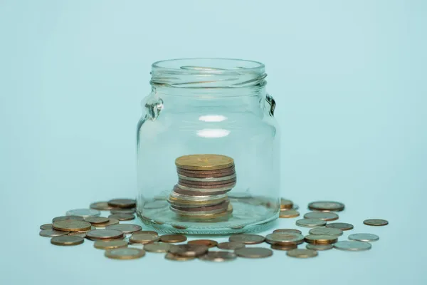 Pot en verre avec de l'argent près de pièces dispersées sur fond bleu, concept anti-corruption — Photo de stock