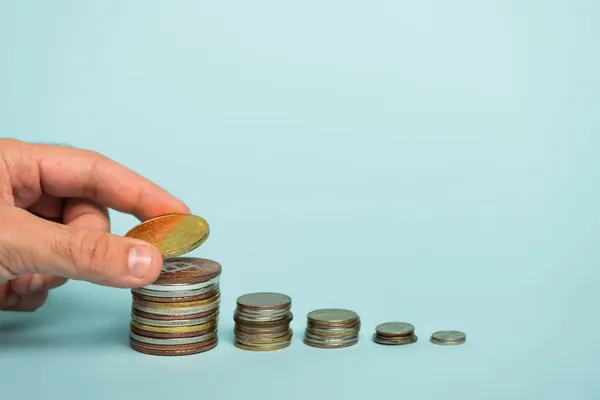 KYIV, UKRAINE - SEPTEMBER 22, 2021: cropped view of man holding bitcoin near stacks of coins on blue, anti-corruption concept — Stock Photo