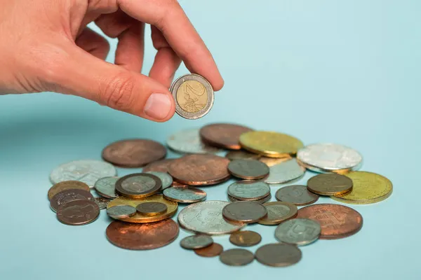 QUIIV, UCRÂNIA - SETEMBRO 22, 2021: visão cortada do homem segurando moeda perto de prata e dinheiro dourado em azul, conceito anti-corrupção — Fotografia de Stock