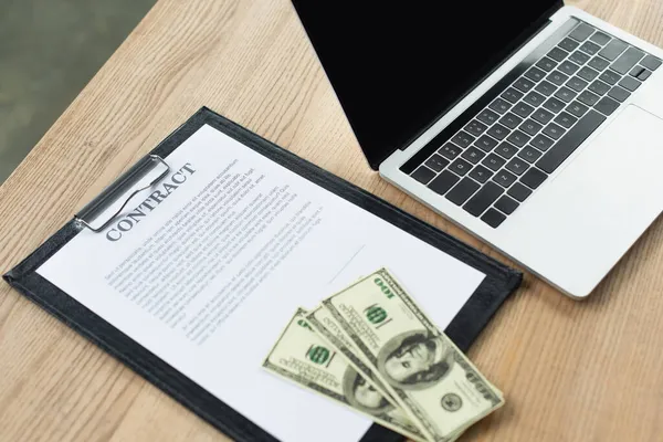 KYIV, UKRAINE - SEPTEMBER 22, 2021: high angle view of dollars on contract near  laptop with blank screen, anti-corruption concept — Stock Photo