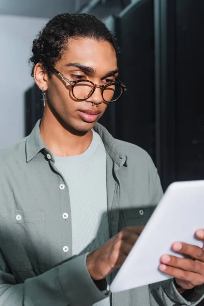 Programmeur afro-américain regardant tablette numérique pendant le travail dans le centre de données — Photo de stock