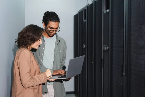 Jovens engenheiros inter-raciais usando laptop enquanto trabalham no data center — Fotografia de Stock