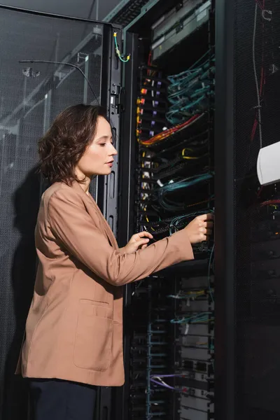 Ingenieur überprüft Drähte des Servers, während er im Rechenzentrum arbeitet — Stockfoto