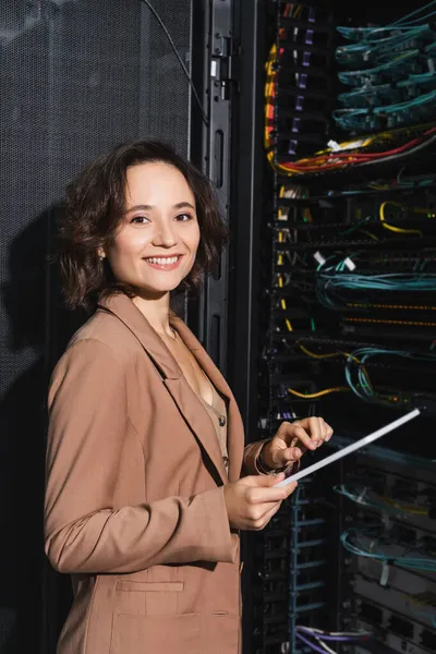 Cheerful engineer with digital tablet looking at camera while making diagnostics of server — Stock Photo