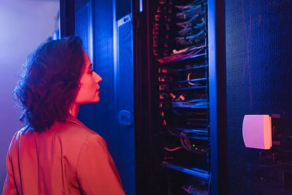 Engenheiro verificando servidor enquanto trabalhava em data center em luz de néon — Fotografia de Stock