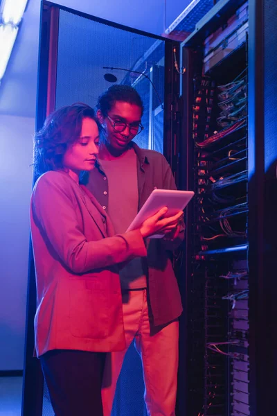 Interracial engineers using digital tablet while checking server in data center — Stock Photo