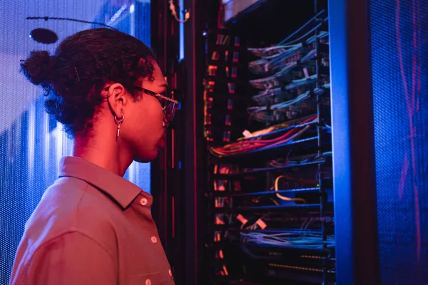 Young african american engineer making diagnostics of server in data center — Stock Photo
