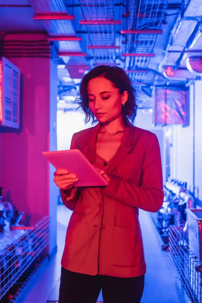 Young engineer using digital tablet in room with technical equipment of data center — Stock Photo