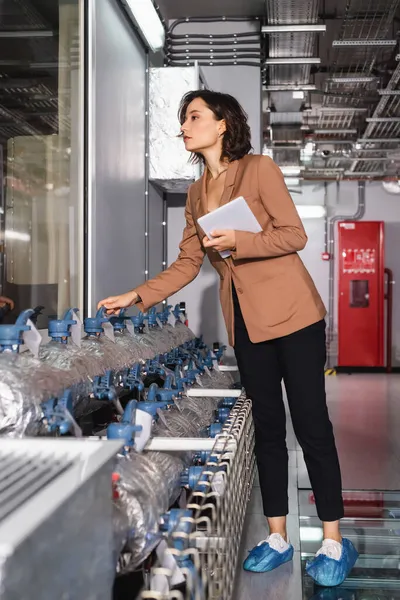 Technical administrator holding digital tablet while standing near cooling system in data center — Stock Photo