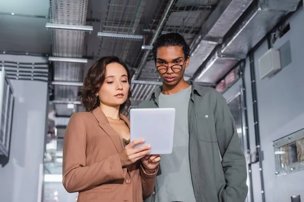 Interracial programmers looking at digital tablet while working in data center — Stock Photo
