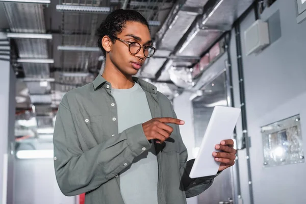 Ingegnere afroamericano che punta al tablet digitale mentre lavora nel data center — Foto stock