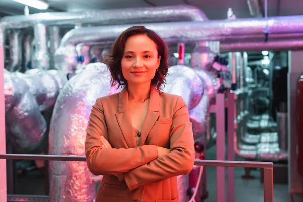 Smiling engineer looking at camera while standing with crossed arms in technical equipment room of data center — Stock Photo