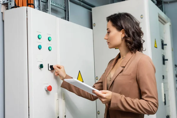 Techniker bedient Schalttafel im Rechenzentrum, während er digitales Tablet hält — Stockfoto