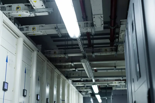 Faible angle de vue des serveurs fermés dans le centre de données avec lampes fluorescentes, concept de cybersécurité — Photo de stock