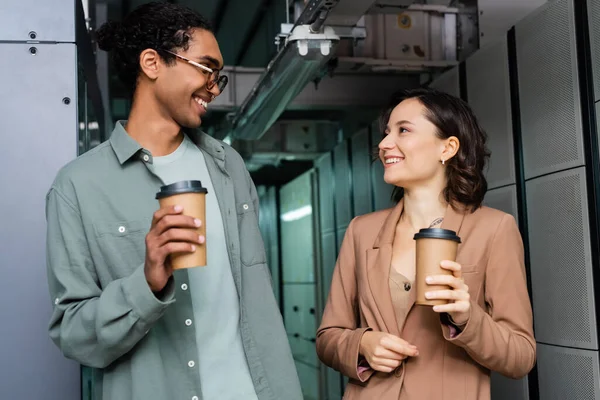 Heureux programmeurs interracial avec des tasses en papier parler dans le centre de données — Photo de stock