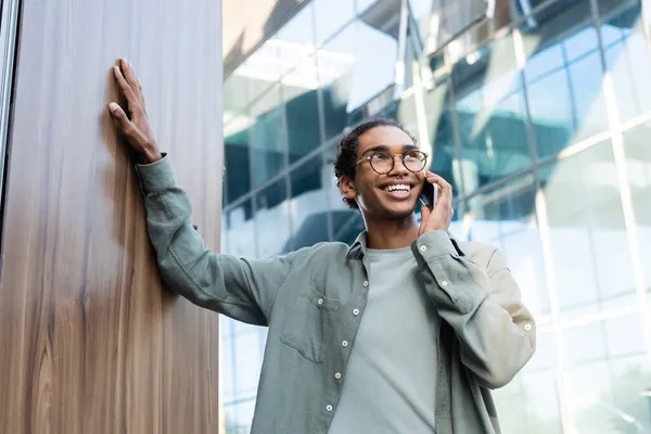 Glücklicher und stilvoller afrikanisch-amerikanischer Mann, der im Freien mit dem Handy telefoniert — Stockfoto