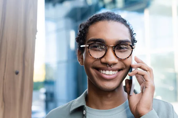 Retrato de homem americano africano em óculos chamando no celular enquanto olha para a câmera — Fotografia de Stock