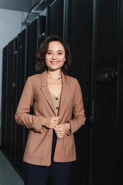 Cheerful engineer smiling at camera while standing in data center — Stock Photo