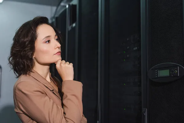 Усвідомлена жінка дивиться на сервер під час роботи в центрі обробки даних — стокове фото