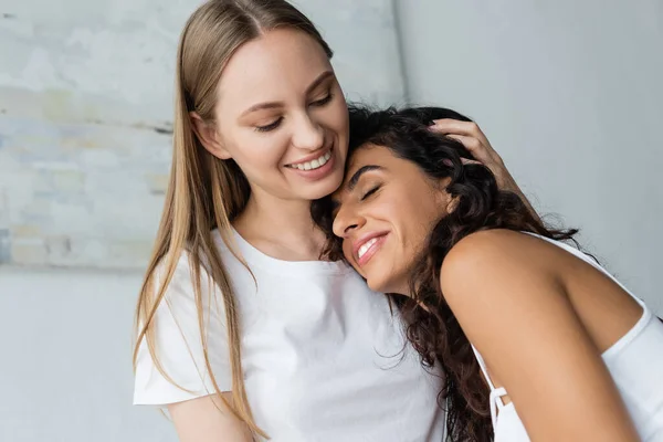 Alegre lesbiana mujer abrazando novia en dormitorio - foto de stock