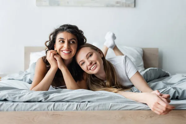 Sourire couple lesbienne couché sur le lit à la maison — Photo de stock
