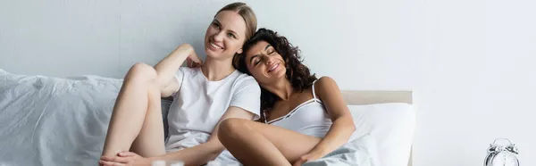 Feliz joven mujer apoyándose en la novia en el dormitorio, pancarta - foto de stock