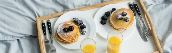 Vista di angolo alta di more su frittelle saporite vicino a occhiali su succo d'arancia su vassoio, stendardo — Foto stock