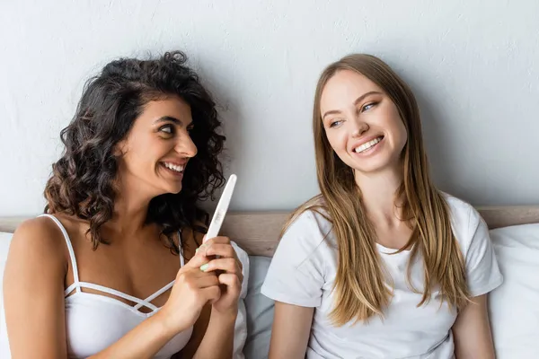 Fröhliche Frau hält Schwangerschaftstest bei glücklicher Freundin ab — Stockfoto