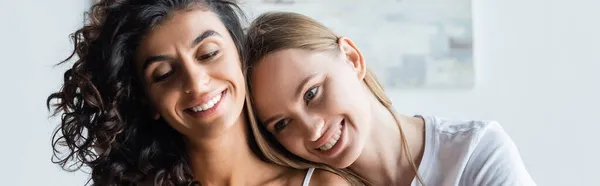 Joven mujer apoyándose en feliz novia en casa, pancarta - foto de stock